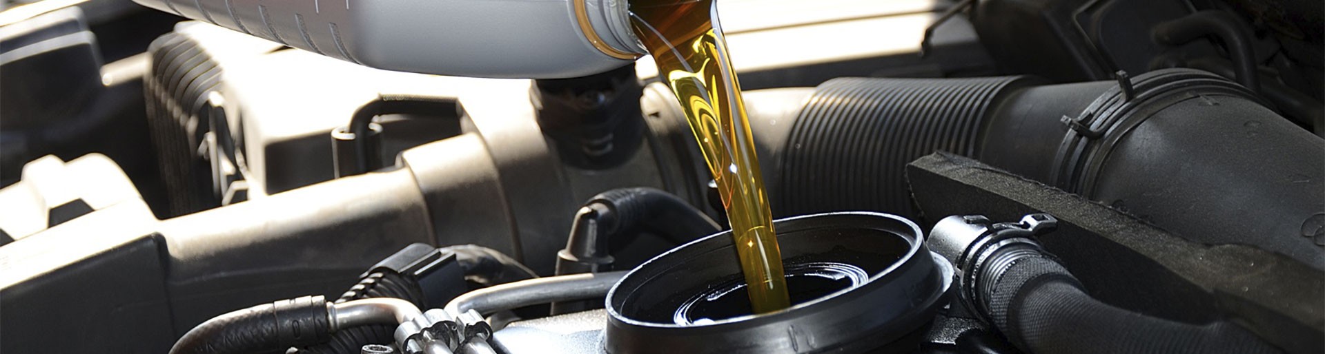 Neues goldfarbenes Motoröl wird aus einer Plastikflasche in den Motor gegeben