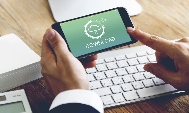 Man holding a mobile phone above keyboard