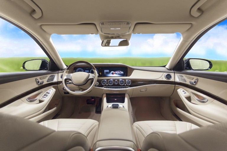 Reduced emissions in the interior Beige colored interior of an upper class car viewing through the wind shield onto a green meadow and a blue sky