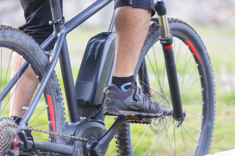 E Bike Legs and sneakers on the pedals of a black e-bike