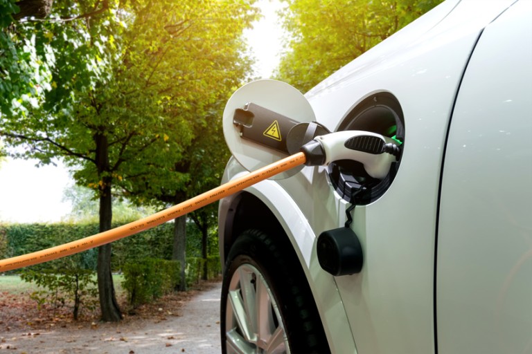 E-Mobility Loading Orange charge cable stuck into the tank opening of a white car
