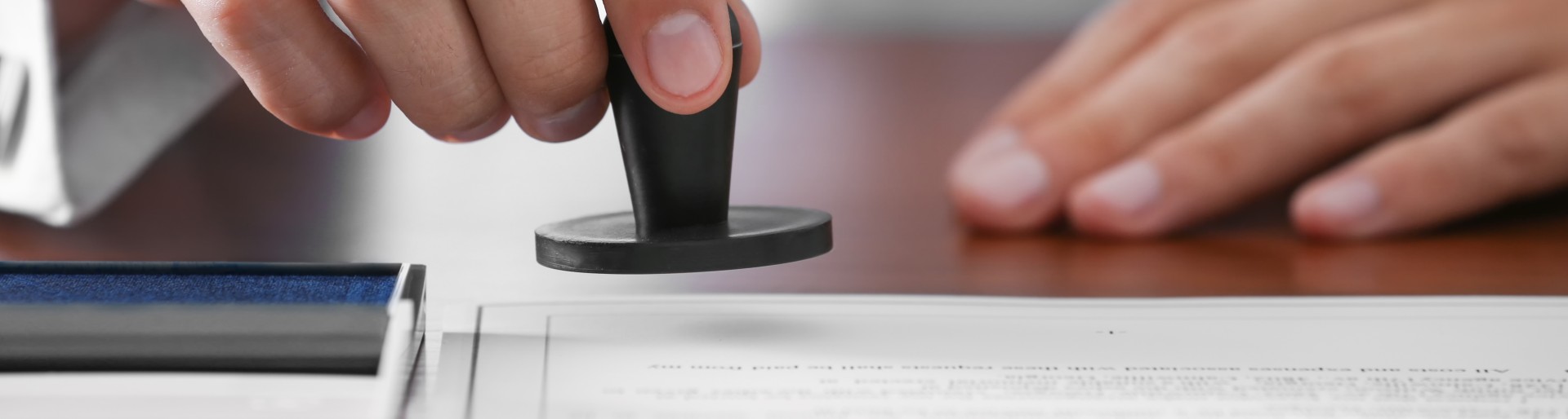 Großaufnahme einer Hand, die einen Stempel auf ein Blatt Papier senkt