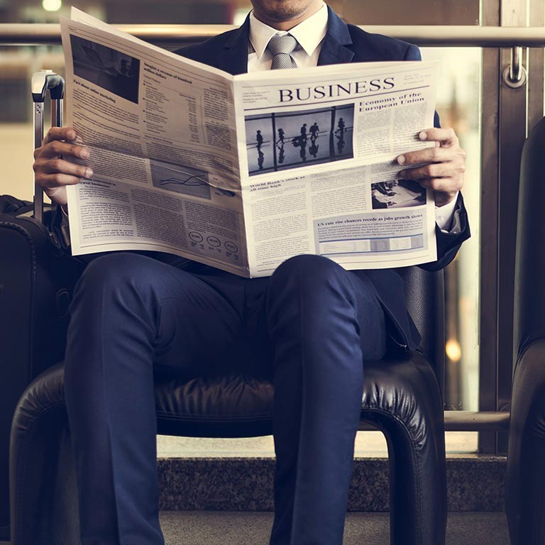 Geschäftsmann sitzt auf einem Stuhl und liest eine Zeitung